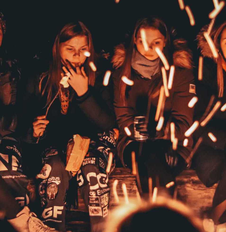 Students gathered around a campfire roasting marshmallows.
