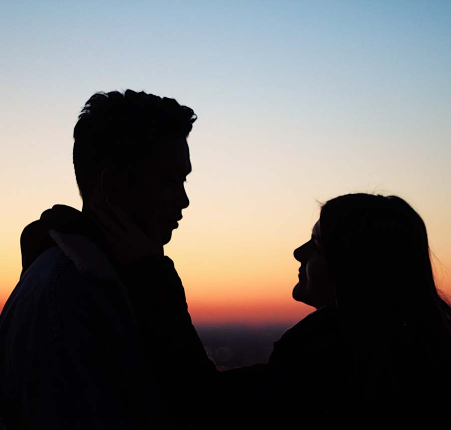 Male and female students looking at each other during sunset. 